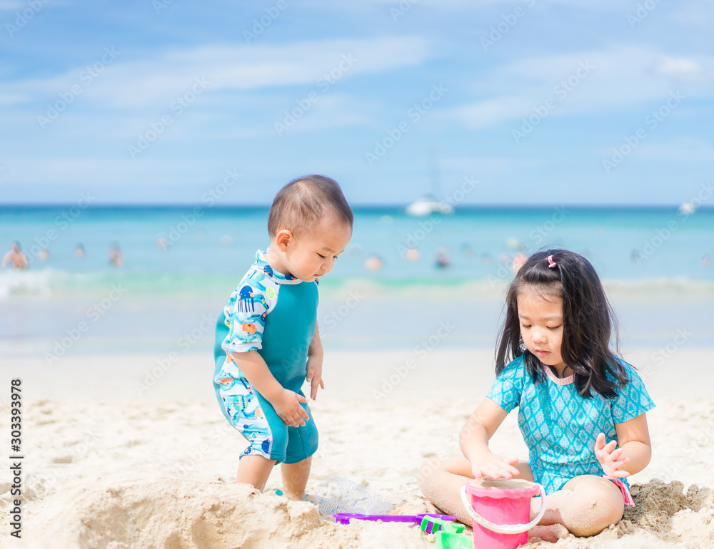 4 years old Little asian girl playing on the beach with her 1 year old baby brother.Family with chil