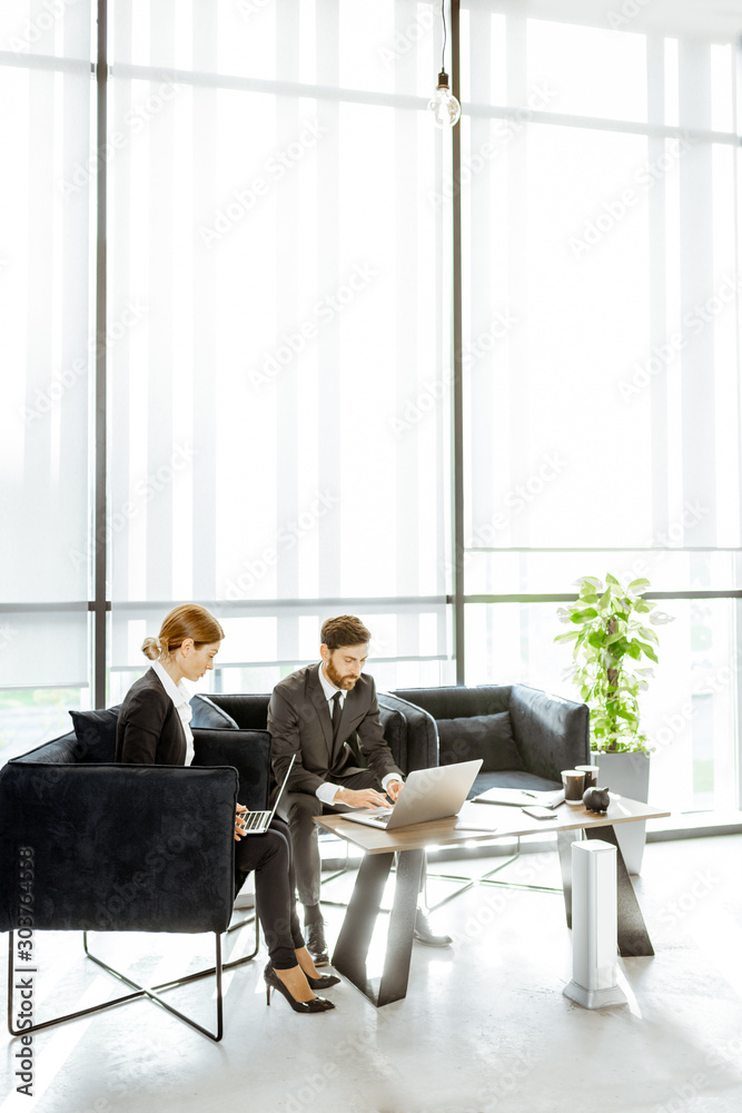 金融机构的白领员工在豪华办公室里用笔记本电脑工作，坐着