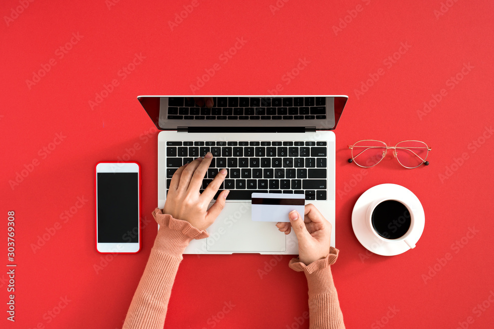 女性在彩色桌子上使用现代笔记本电脑，俯视图