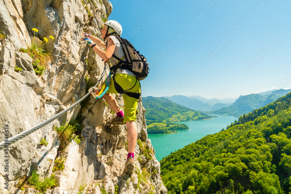 Beautiful young girl climbing Drachenwand via ferrata above scenic Mondsee lake, Alps, Austria, Euro