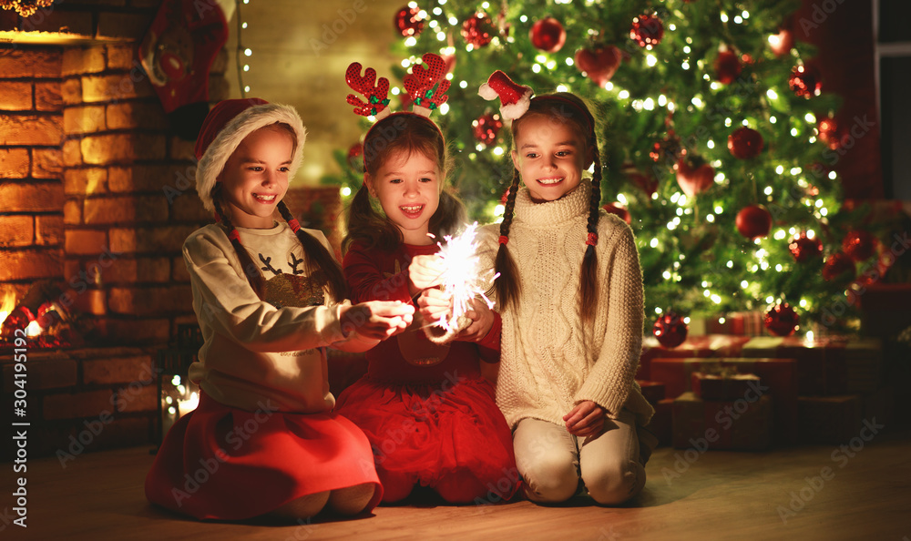 快乐快乐的孩子们在圣诞树旁燃放烟花。