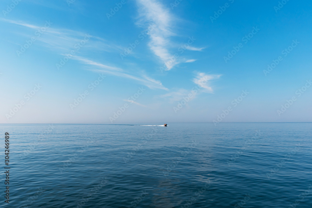 在一个灿烂的阳光明媚的日子里，船在海上巡航，留下了尾迹。美丽的蓝天和淡淡的白色木屐
