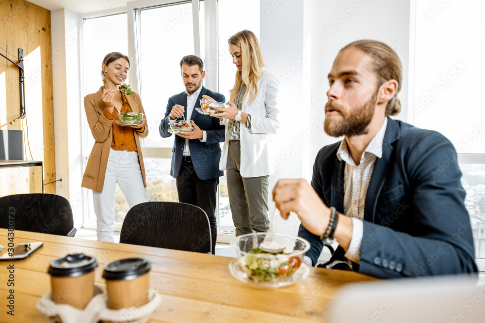 一群年轻的上班族在现代办公室食堂吃沙拉、喝咖啡。Conc