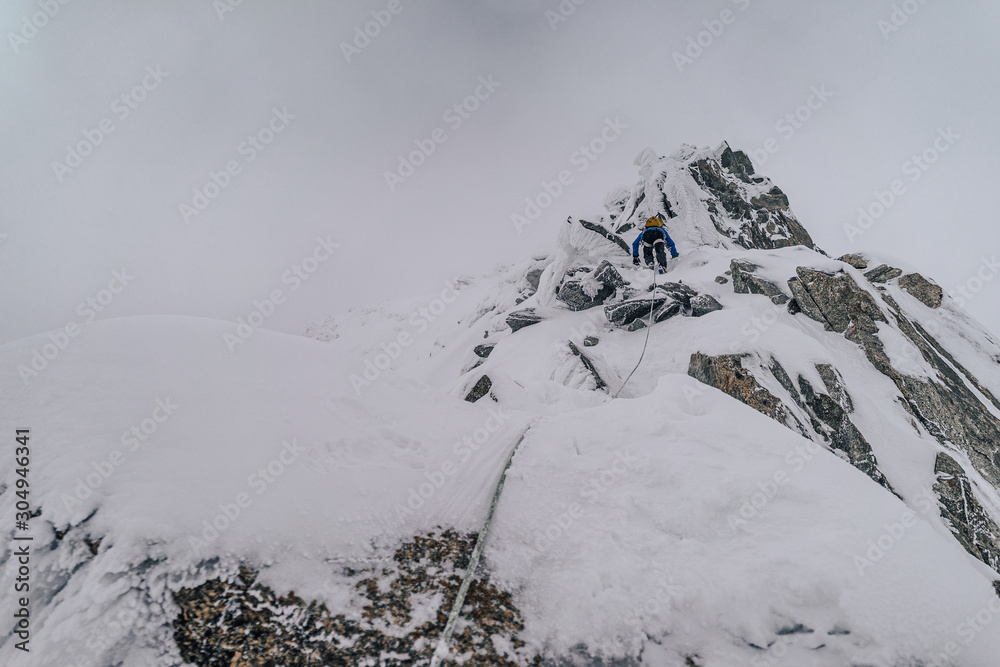 一名登山运动员在冬季极端条件下攀登高山山脊。冒险攀登高山i峰