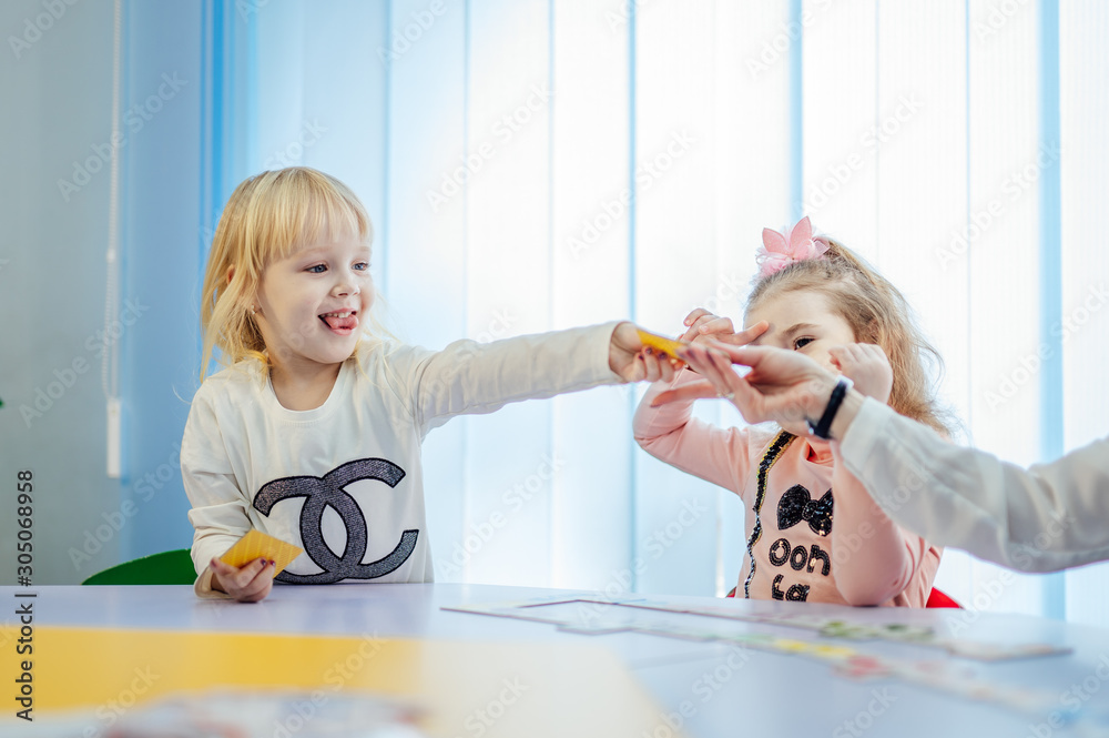 Two beautiful little cute girls preschoolers playing in classroom. New methods of education. Shool c