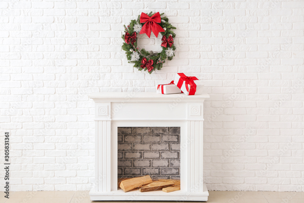 美丽的圣诞花环挂在壁炉附近的墙上，上面有礼品盒