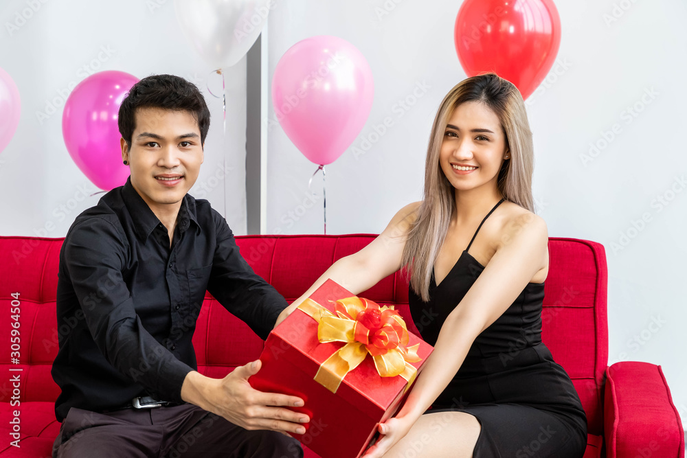 有魅力的年轻情侣一起庆祝周年纪念日。男人给女人送礼物礼盒。
