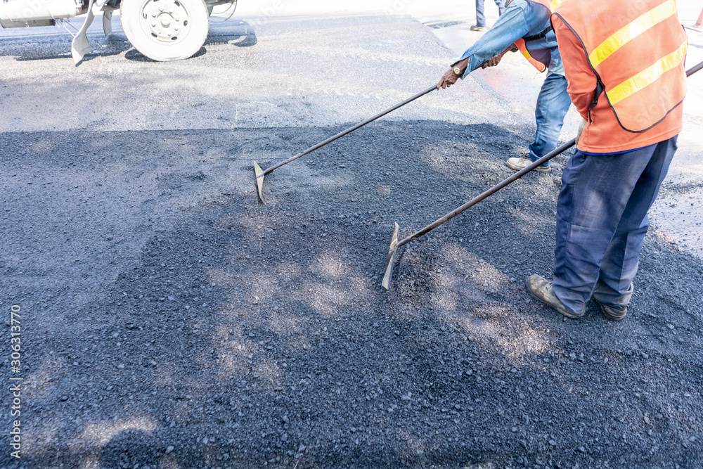 Road worker making road use rakp for swab asphalt for working.