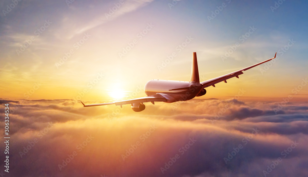 乘客乘坐的商用飞机在日落的阳光下飞越云层。快速旅行的概念，假期