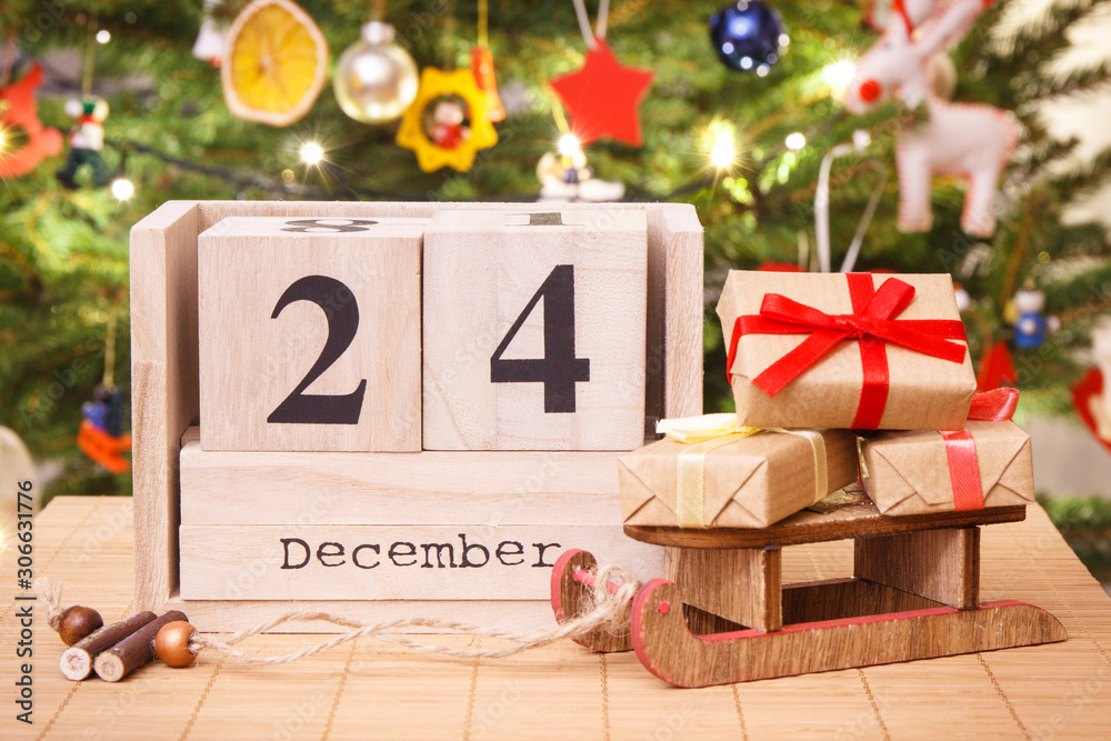 日期为日历上的12月24日，包装好的礼物和带装饰的圣诞树，圣诞节前夕时间c
