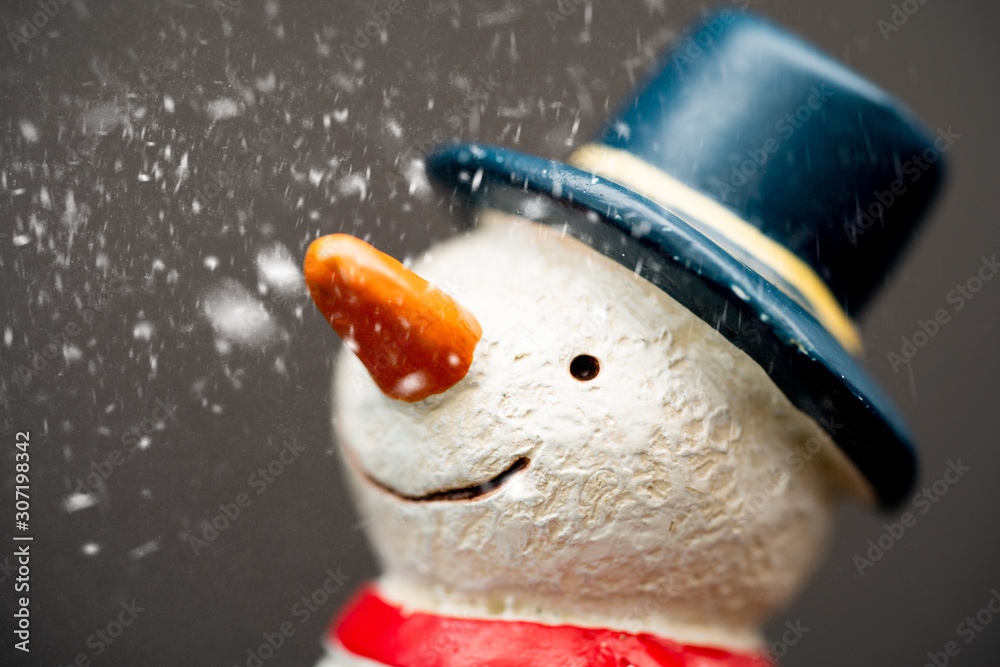 快乐的笑脸雪人，戴着蓝色帽子，长着胡萝卜鼻子，与雪花站在冬季圣诞的海洋中