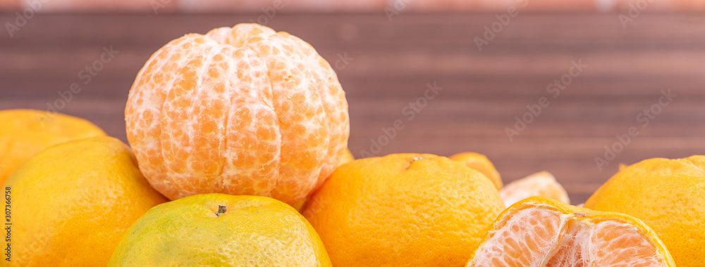 Peeled tangerines in a bamboo sieve basket on dark wooden table with red brick wall background, Chin