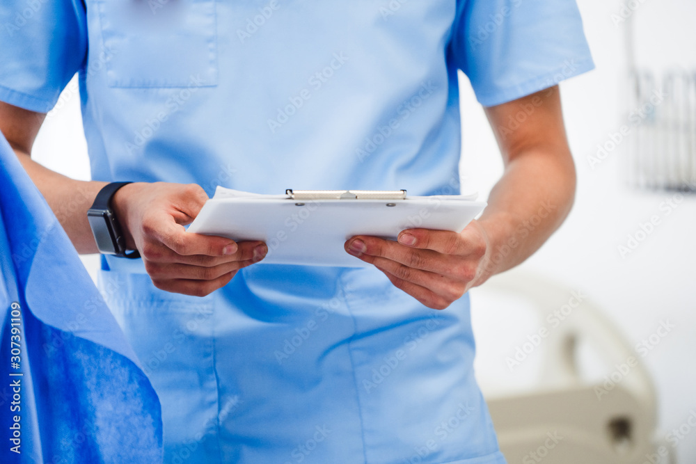 男医生穿着磨砂膏从检查表文件中读取患者信息，选择性聚焦