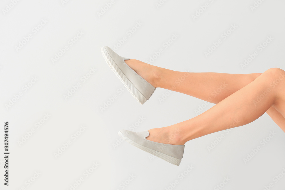 Young woman in stylish shoes on light background