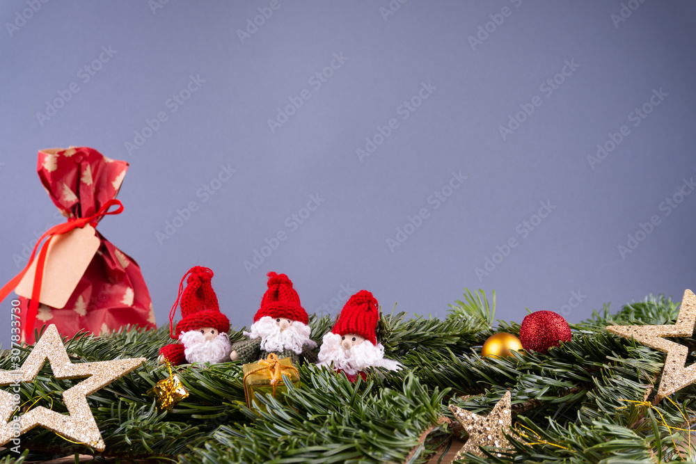 Christmas ornaments (dwarfs, present, stars, baubles) and fir twigs in front of a gray background