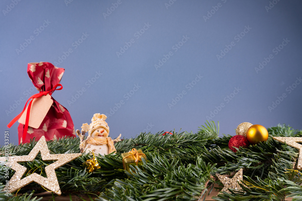 灰色背景前的圣诞饰品（雪人、礼物、星星、小玩意）和冷杉枝