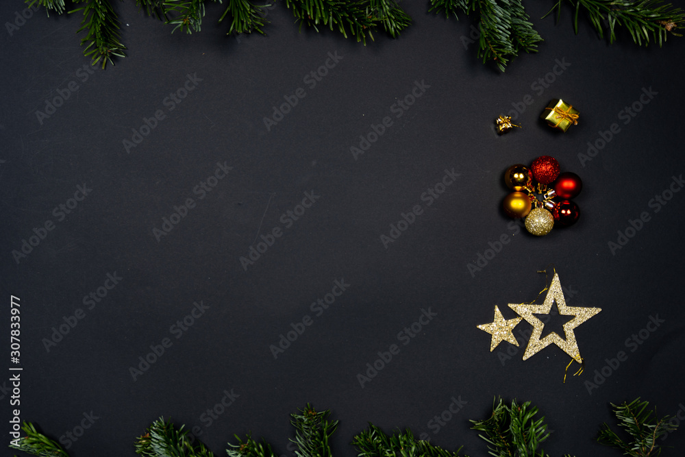 黑色背景下的圣诞装饰品（圣诞饰品、星星和小礼物），由冷杉框起来