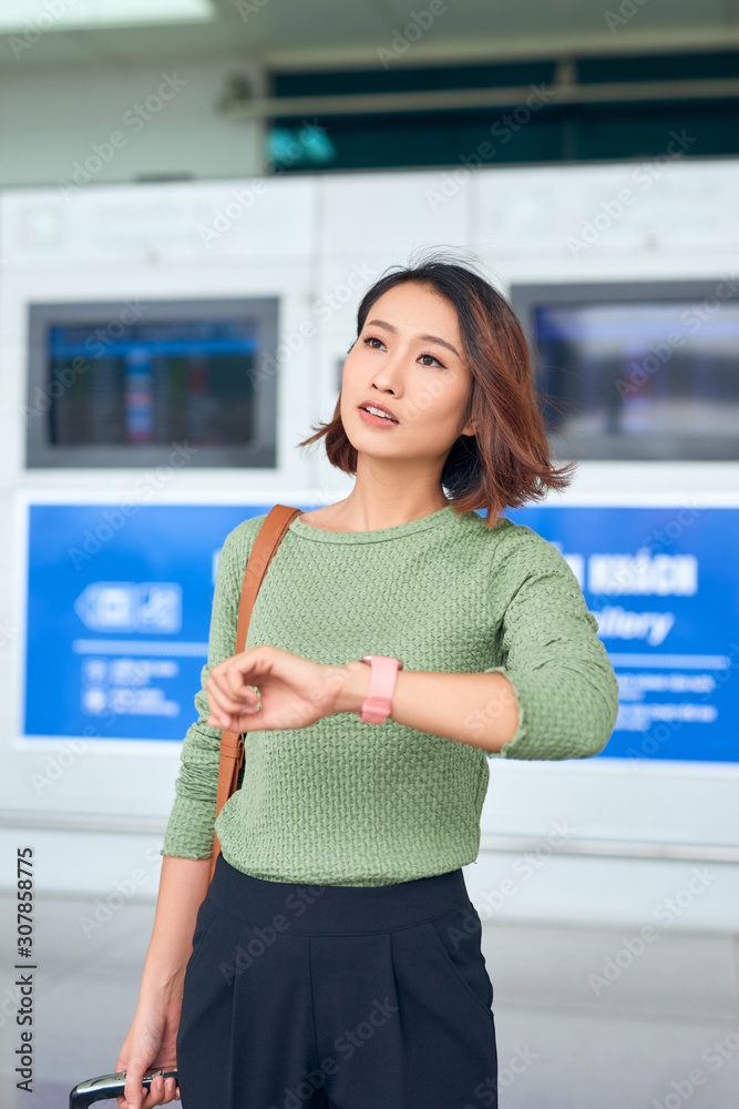 美丽的亚洲女人看着手表看时间。