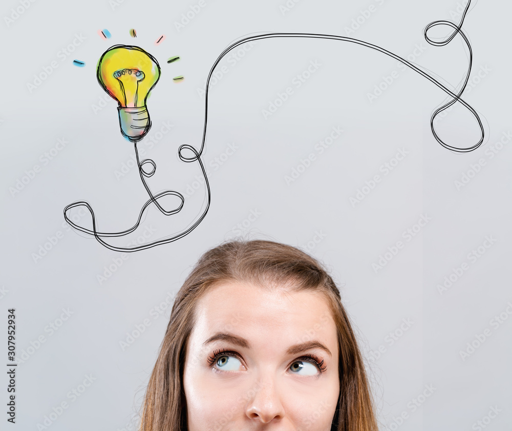Light bulb with string with young woman looking upwards