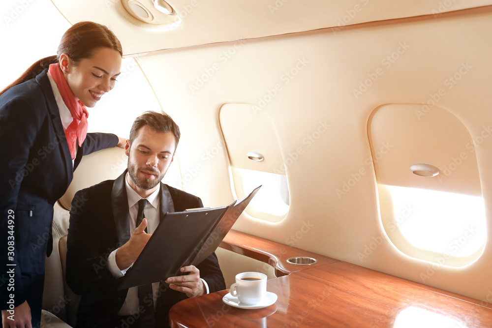 空姐在现代私人飞机上向商人展示菜单