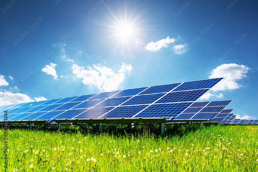 阳光下的蓝天下的太阳能电池板。绿草和多云的天空。替代能源概念