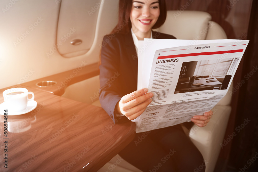 女商人在现代私人飞机上读报