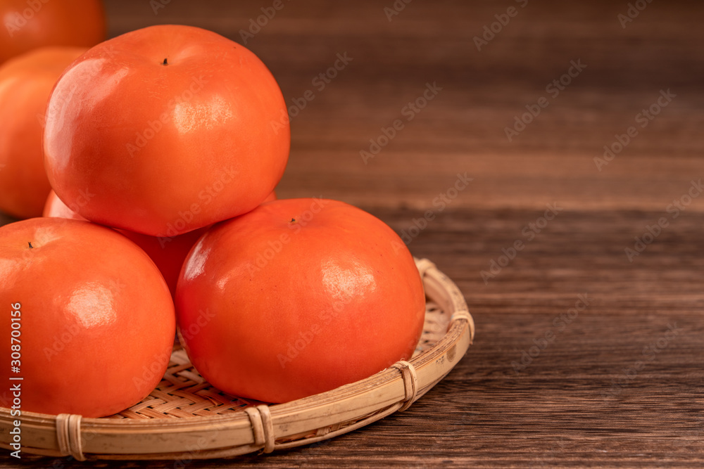 竹篮子里的柿子切片，放在深色木桌上，红砖墙背gr