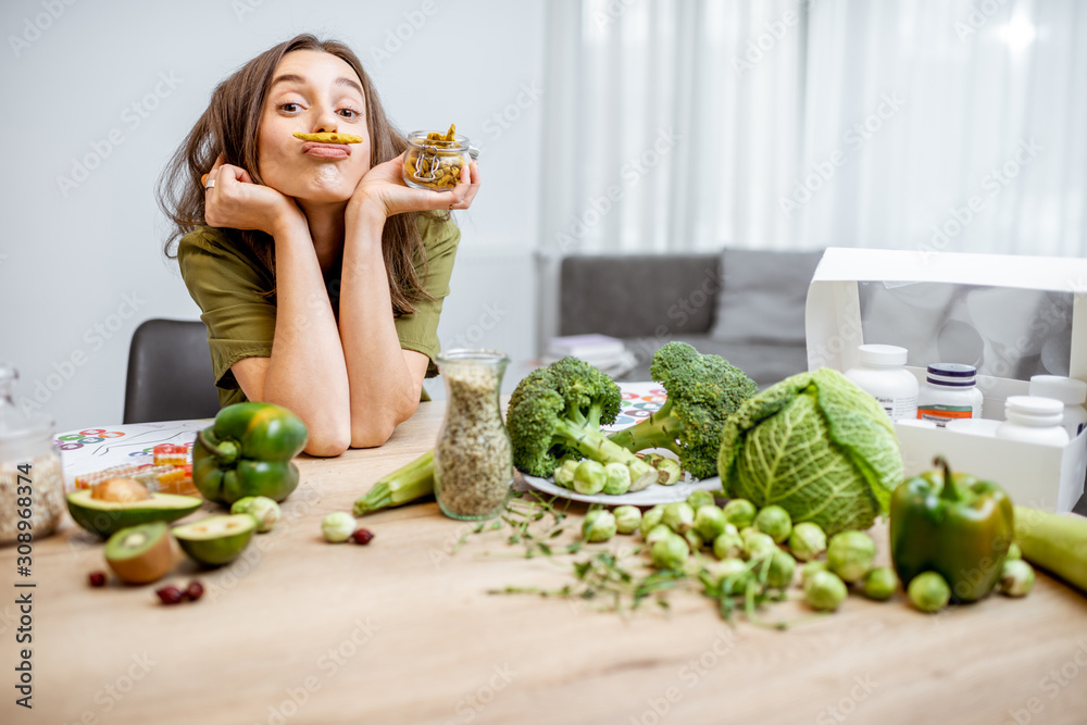 一个年轻快乐的女人的画像，桌上有很多健康的绿色食物。蔬菜的概念
