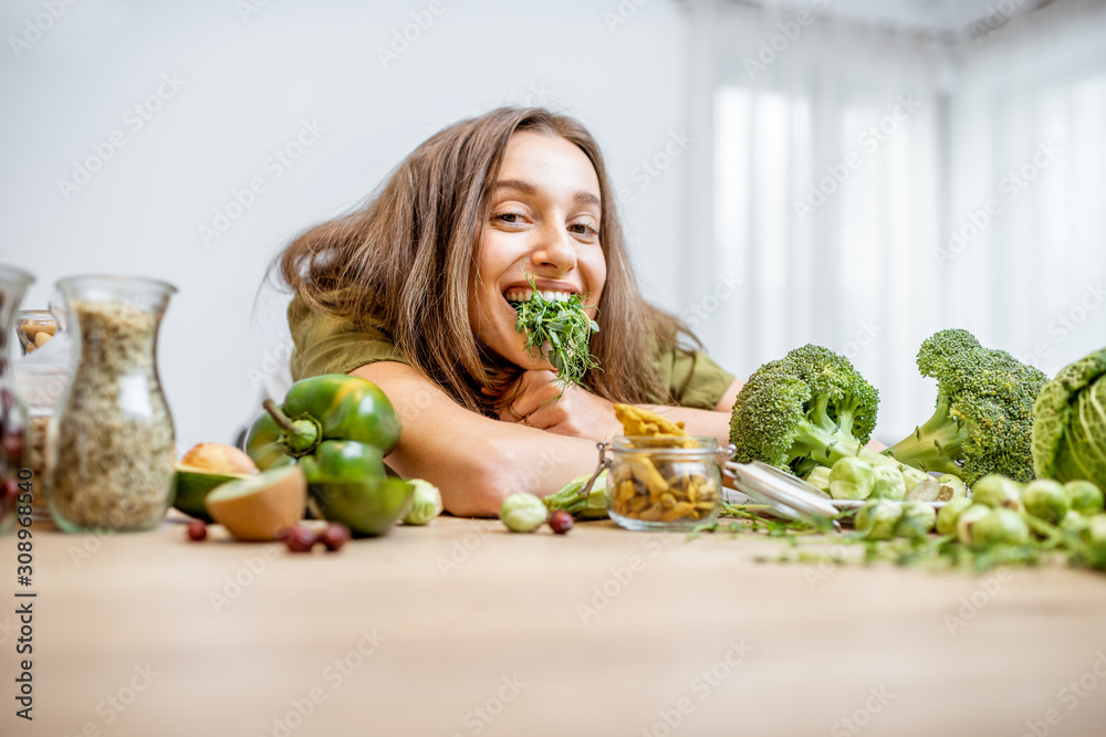 一个年轻快乐的女人的画像，桌上有豌豆苗和很多健康的绿色食物。C