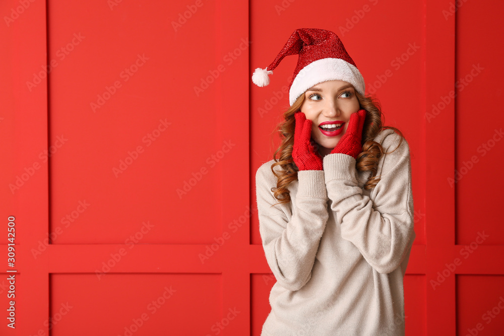 Surprised young woman in winter clothes on color background