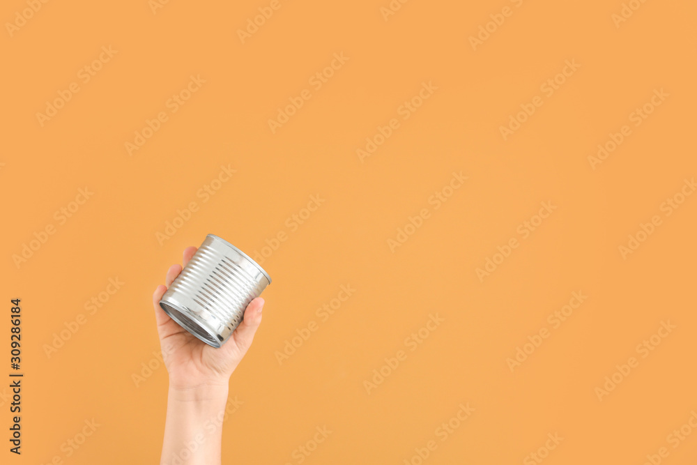 Hand with empty tin can on color background. Concept of recycling