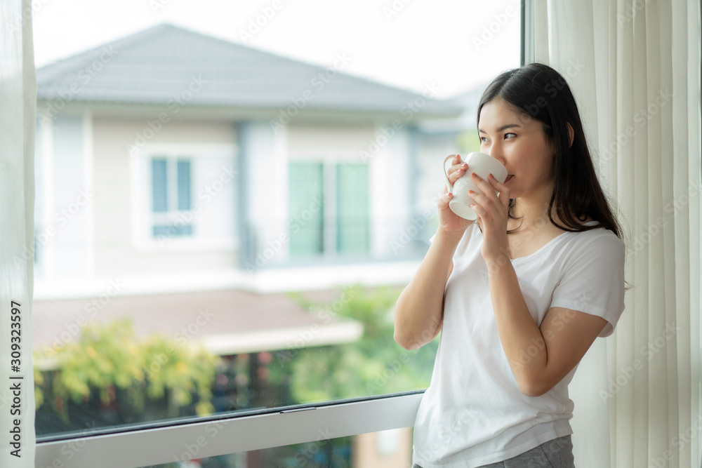 Beautiful Asian woman wake up in her bed fully rested and open the curtains on the windowsill and lo