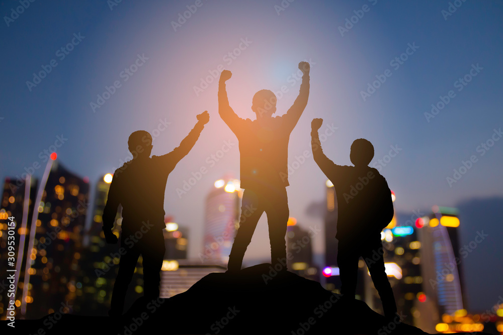 快乐团队合作的剪影，举起手来表示成功、胜利并在t中实现商业目标