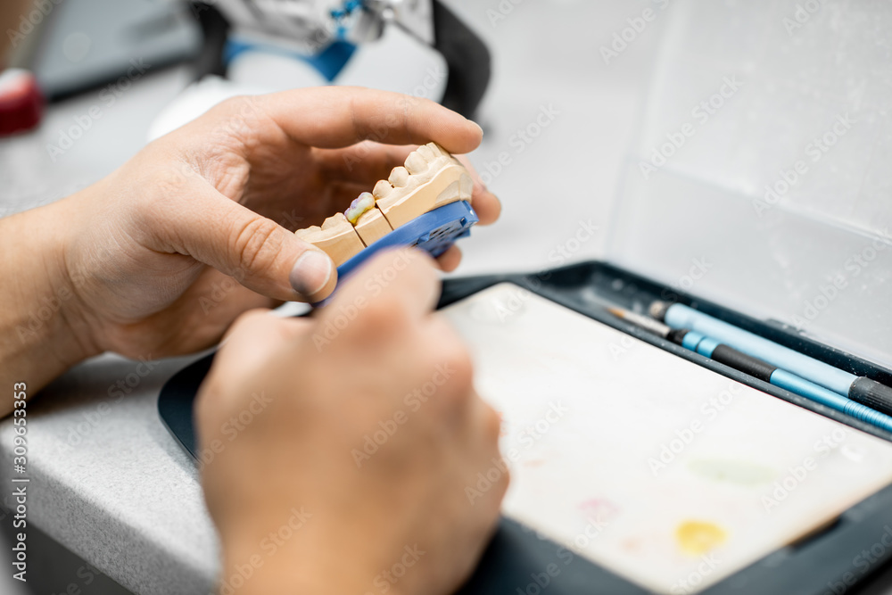 牙科技师在实验室用画笔为假牙上色，特写。Co