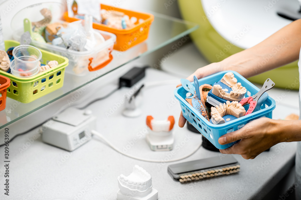 牙科技师，容器里装满了各种人工下颌模型、印模和假牙