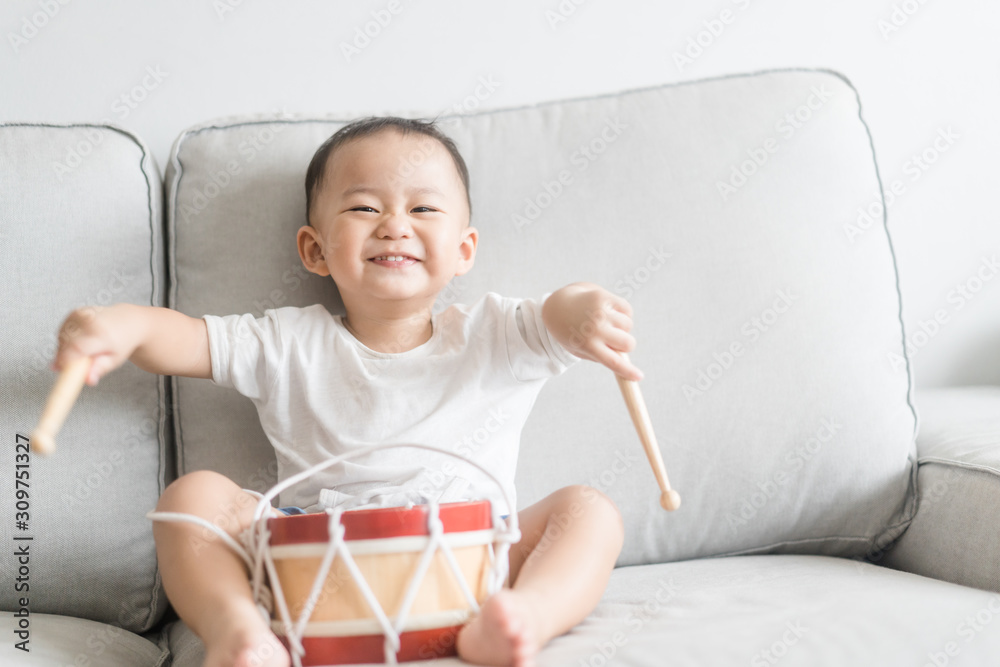 小鼓手男孩在家里打鼓。亚洲男孩弹唱快乐