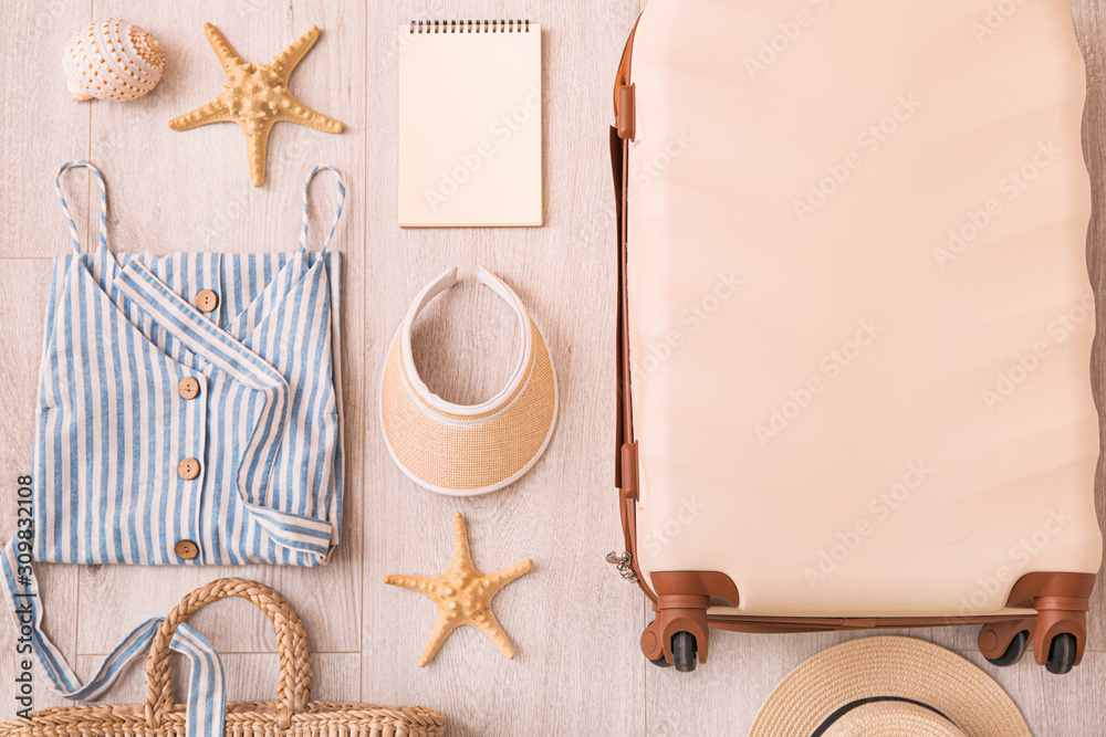 Suitcase with female clothes and travel accessories on wooden background