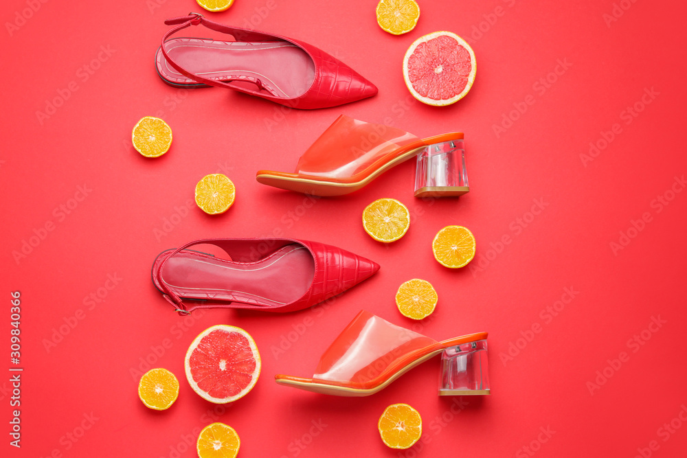 Stylish female shoes and citrus fruits on color background