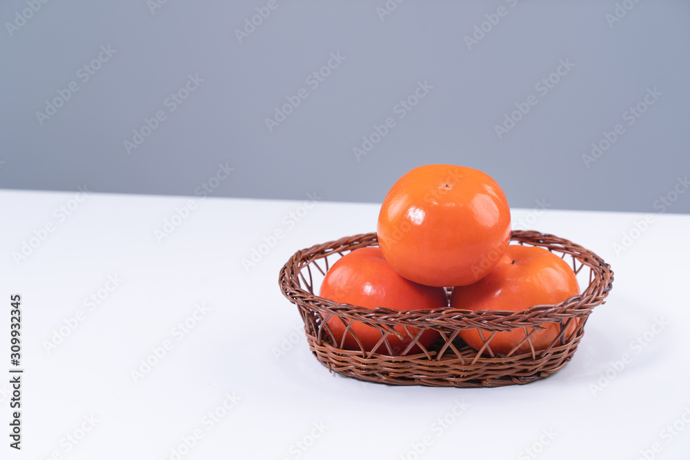 Fresh beautiful sliced sweet persimmon kaki isolated on white kitchen table with gray blue backgroun