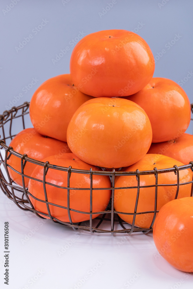 新鲜漂亮的甜柿子切片，隔离在灰蓝色背景的白色餐桌上