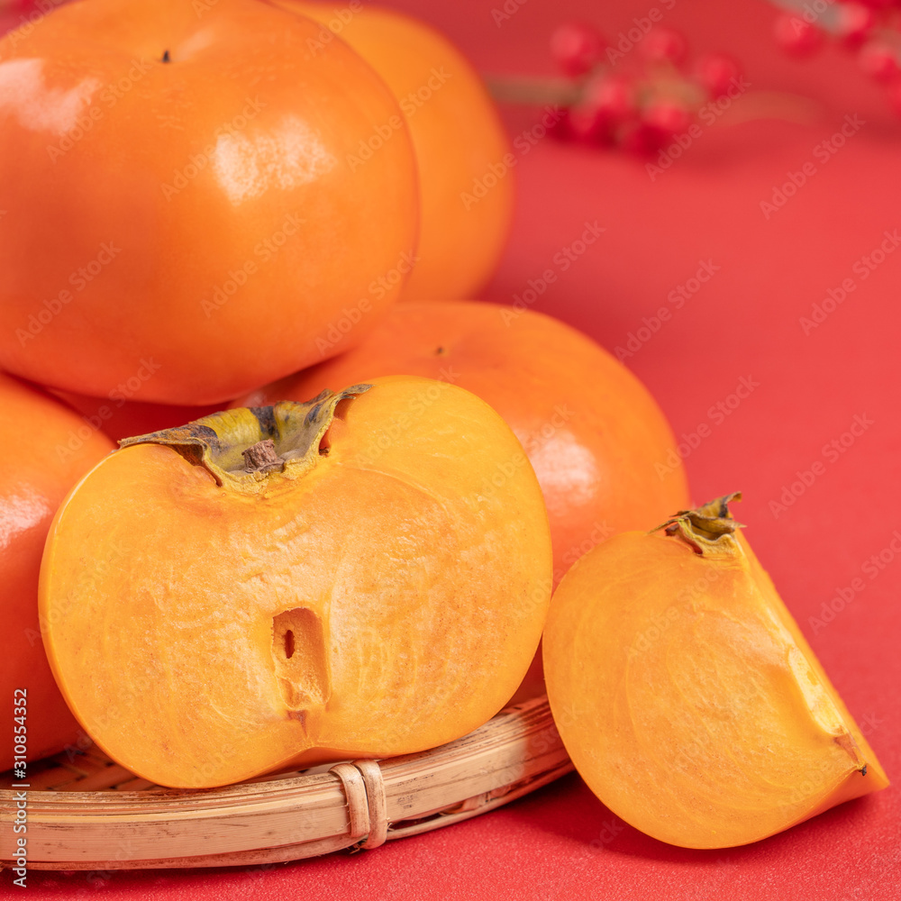 新鲜美丽的切片甜柿子，分离在红色桌子背景和竹筛上，中国