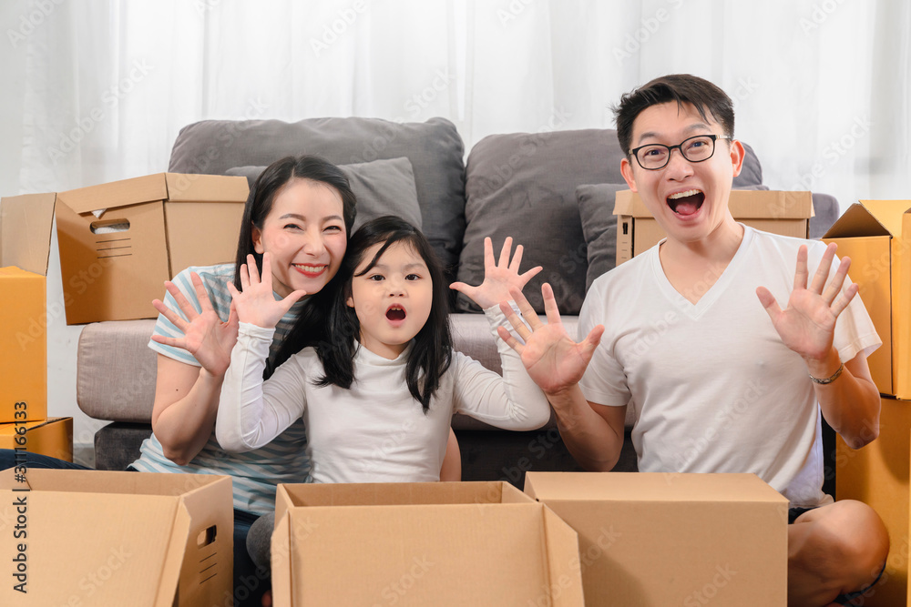 亚洲幸福家庭微笑着看着相机，带着离开和握手在新家打开东西