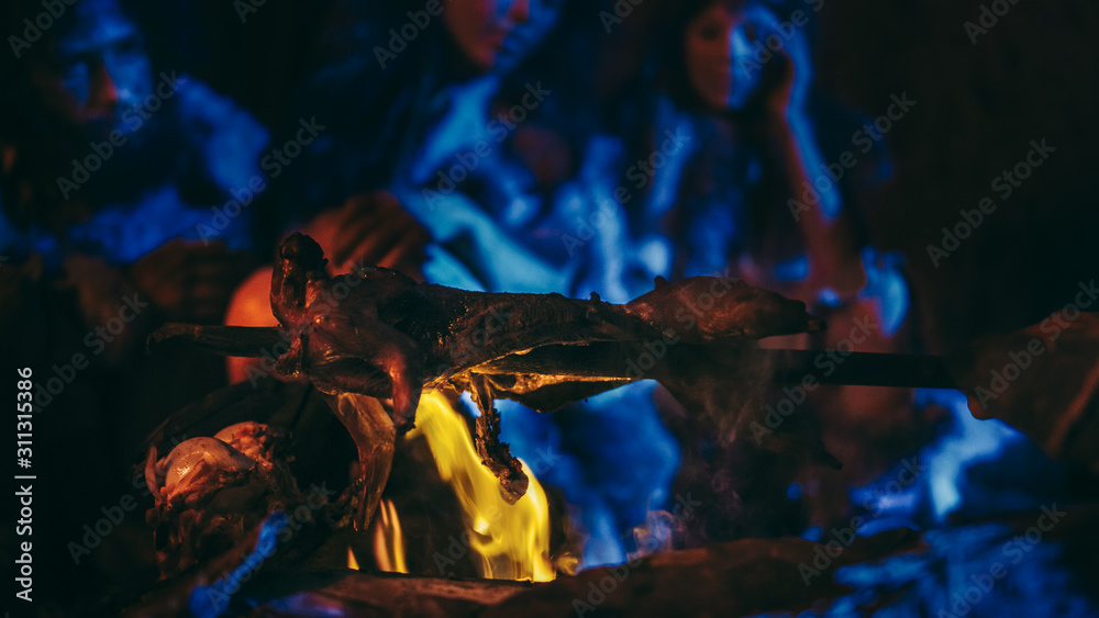 尼安德特人或智人家族在篝火上烹饪动物肉，然后食用。史前部落