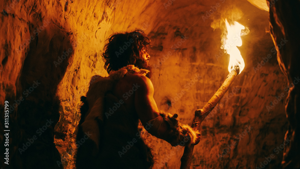 原始洞穴人穿着兽皮在夜间探索洞穴，手持火炬与火焰Lo的肖像