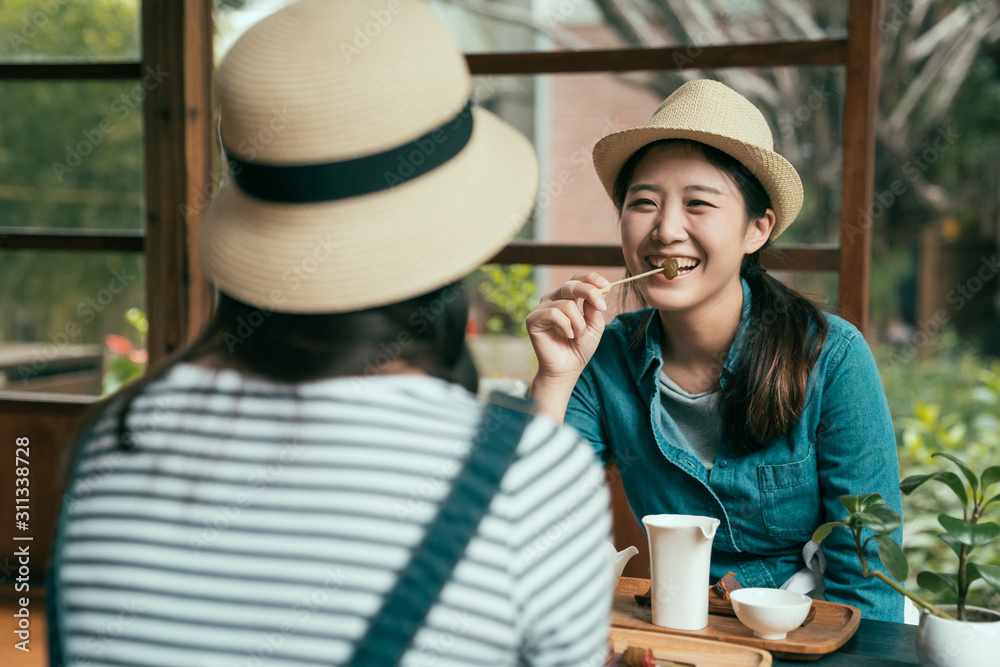 Smiling asian korean female friends drinking matcha tea and laughing. lady in straw hat eating plum 