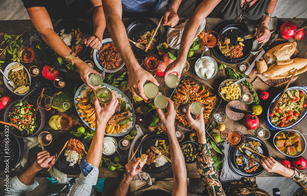 一家人在餐桌上碰杯，享用土耳其美食羊排、木瓜、豆子、蔬菜