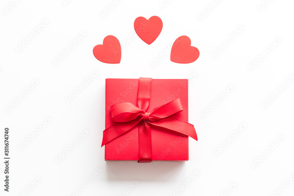 情人节送给爱人的礼物。白色背景上靠近心形的红色礼物盒自上而下。