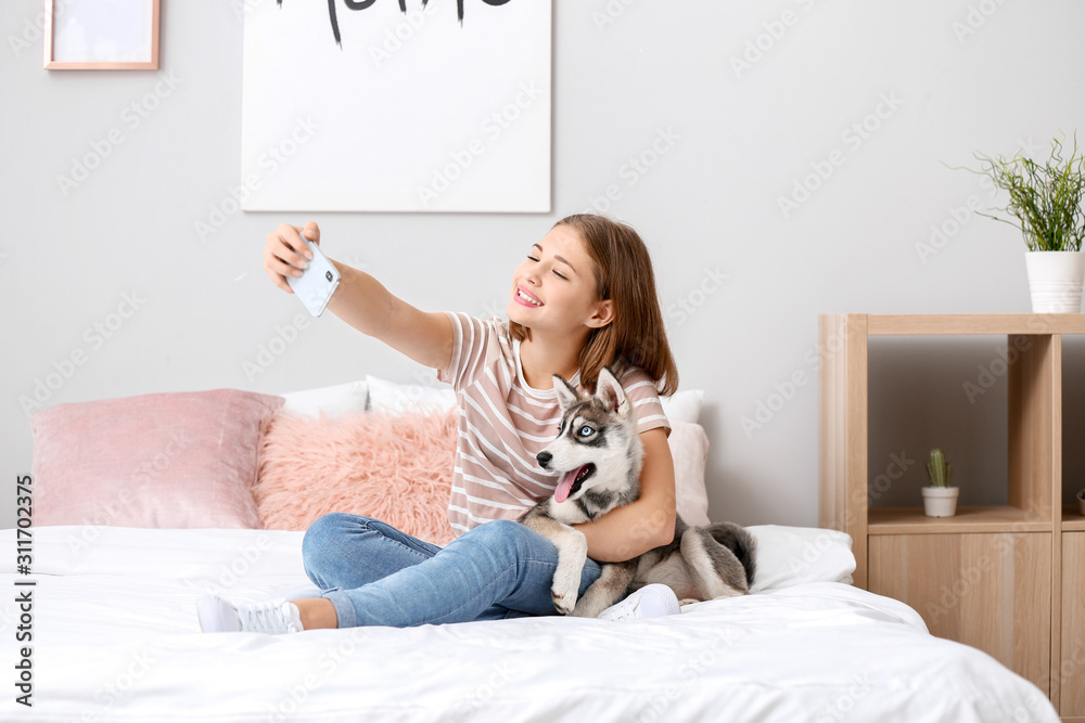 可爱的十几岁女孩和有趣的哈士奇小狗在家里的床上自拍
