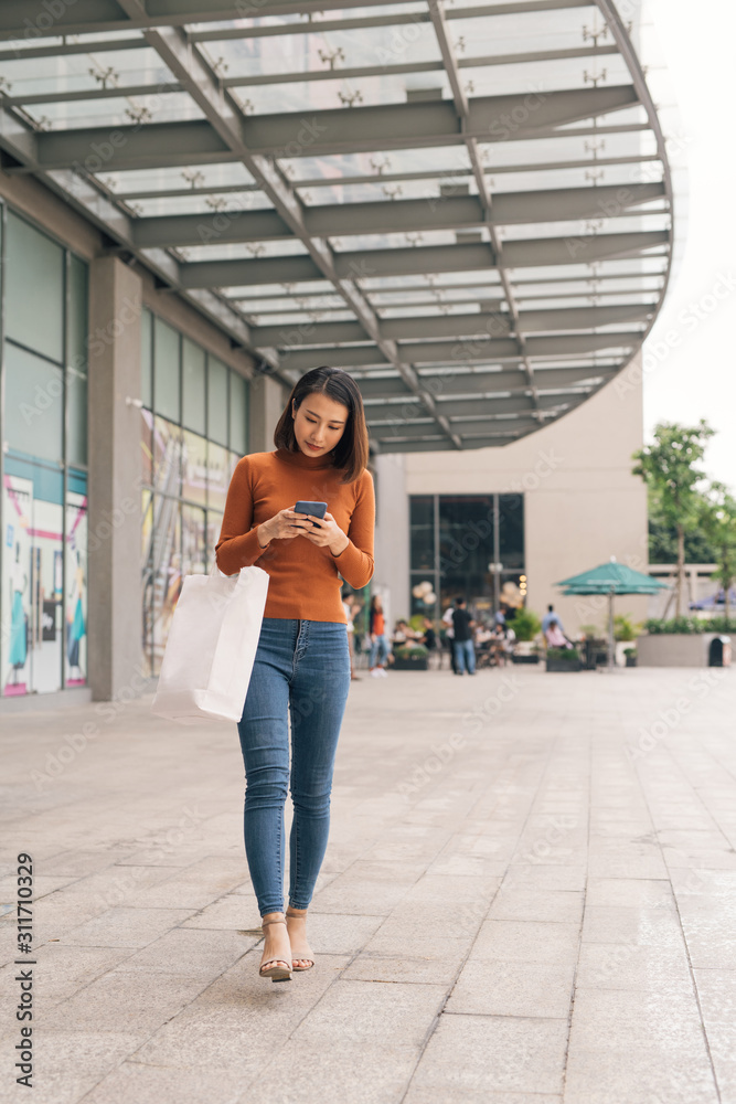 亚洲女性在户外购物中心购物并使用手机