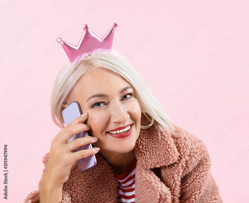 酷时尚的成熟女性在彩色背景下用手机交谈